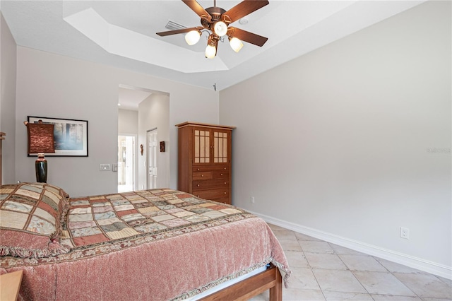 bedroom with light tile patterned floors, a tray ceiling, and ceiling fan