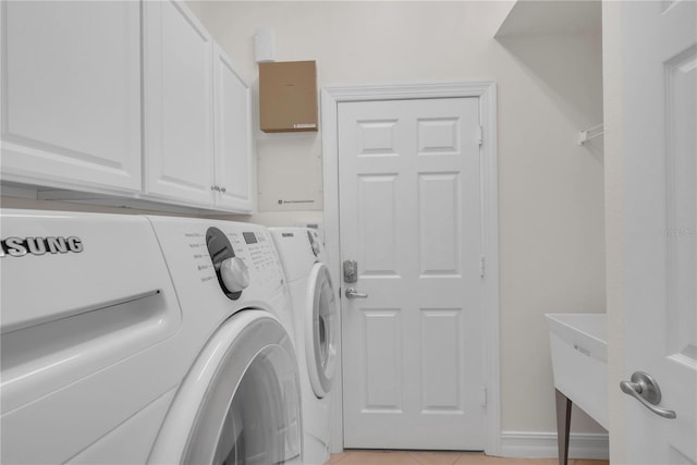 laundry area with cabinet space, light tile patterned floors, a sink, baseboards, and washer and clothes dryer
