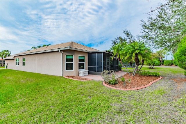 rear view of property with a yard, stucco siding, a sunroom, and a tile roof