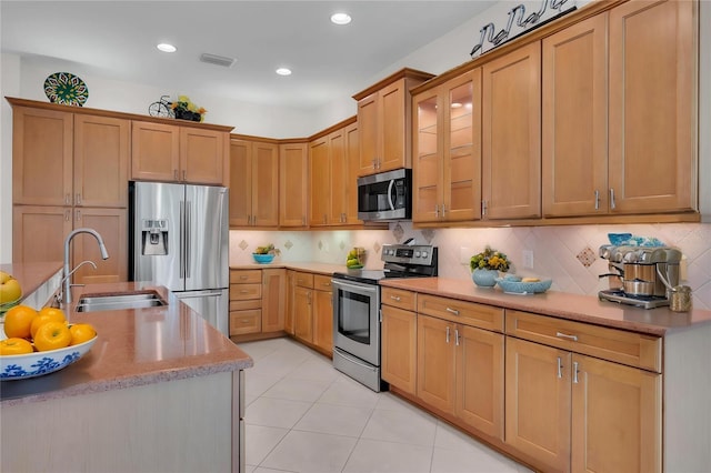 kitchen featuring visible vents, a sink, backsplash, light tile patterned floors, and stainless steel appliances