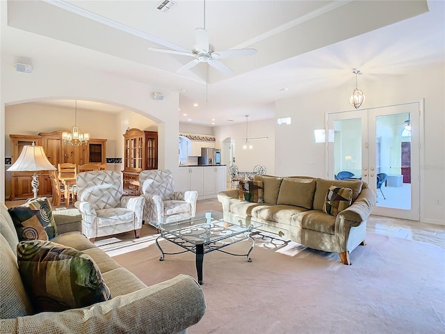 living room featuring light carpet, french doors, and ceiling fan with notable chandelier