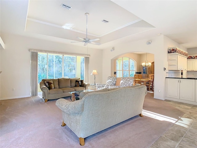 living room featuring ceiling fan with notable chandelier, light colored carpet, a raised ceiling, and ornamental molding