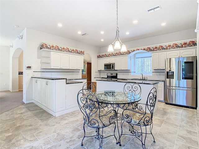 kitchen featuring a center island, sink, hanging light fixtures, white cabinets, and appliances with stainless steel finishes