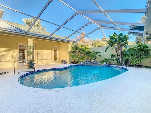 view of pool with glass enclosure and a patio