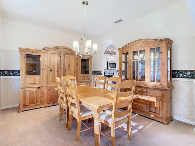 dining space featuring a notable chandelier, visible vents, light colored carpet, and a wainscoted wall