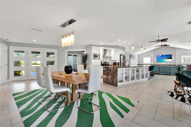 dining room with ceiling fan with notable chandelier, vaulted ceiling, and sink