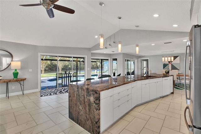 kitchen with stainless steel fridge, white cabinetry, a large island with sink, and sink