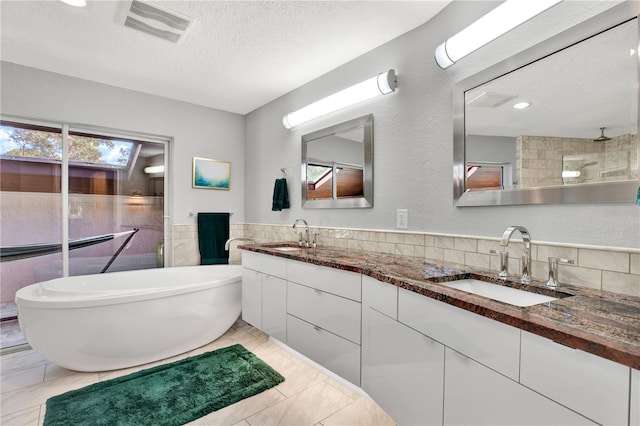 bathroom with vanity, a bath, and a textured ceiling