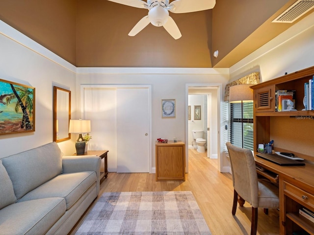 living room with a high ceiling, light hardwood / wood-style floors, and ceiling fan