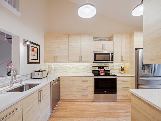 kitchen with hanging light fixtures, sink, light wood-type flooring, light brown cabinetry, and stainless steel appliances