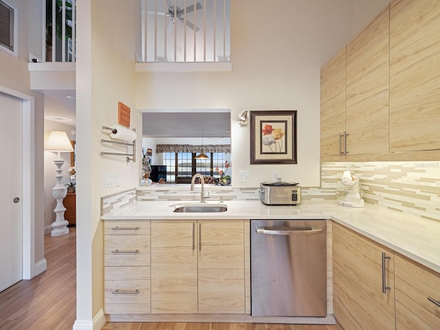 kitchen featuring dishwasher, sink, light wood-type flooring, light brown cabinetry, and tasteful backsplash