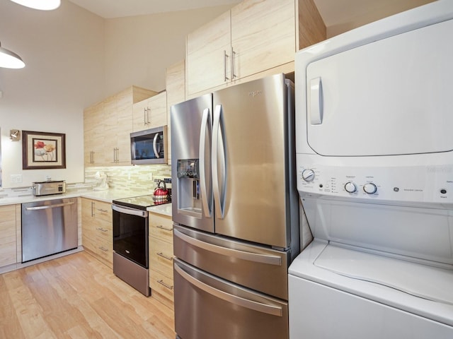 kitchen featuring decorative backsplash, light wood-type flooring, stacked washing maching and dryer, stainless steel appliances, and light brown cabinets