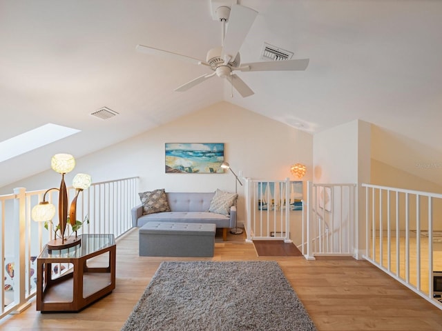 sitting room with light hardwood / wood-style floors, ceiling fan, and vaulted ceiling with skylight