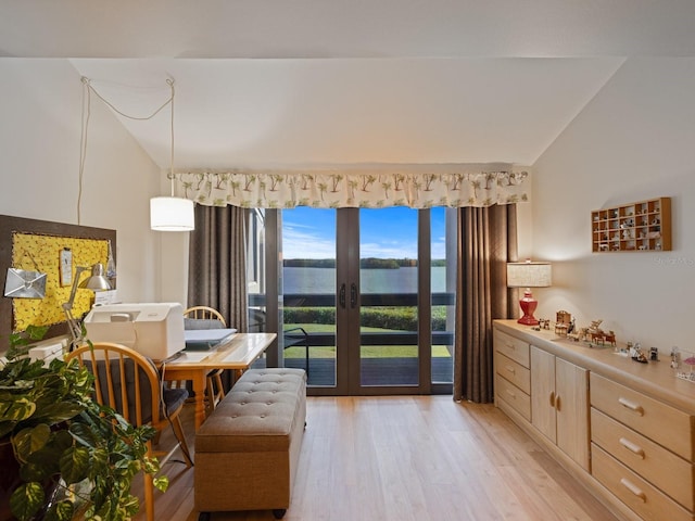 living area featuring light wood-type flooring, a water view, and lofted ceiling