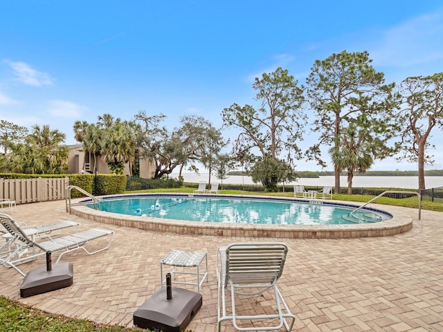 view of swimming pool featuring a patio and a water view