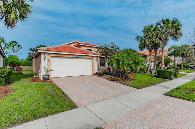 mediterranean / spanish-style home featuring a tiled roof, decorative driveway, a garage, a front lawn, and stucco siding