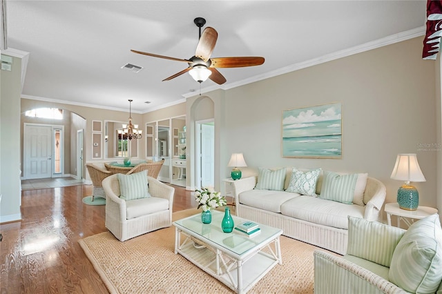 living room featuring hardwood / wood-style floors, ceiling fan with notable chandelier, and ornamental molding