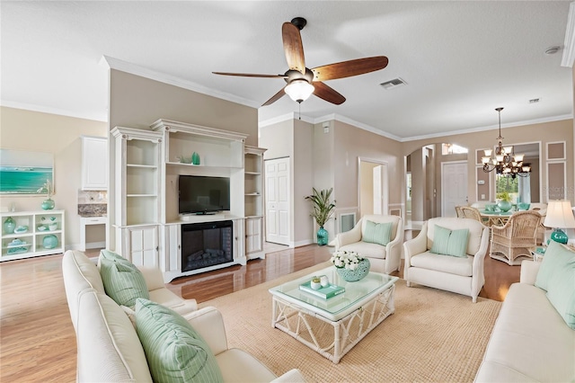 living room with ceiling fan with notable chandelier, light hardwood / wood-style flooring, and ornamental molding