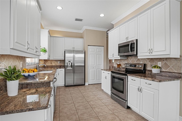 kitchen featuring dark stone counters, white cabinetry, light tile patterned floors, and stainless steel appliances