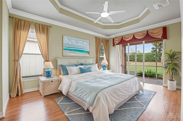 bedroom featuring access to exterior, a tray ceiling, ceiling fan, crown molding, and hardwood / wood-style floors