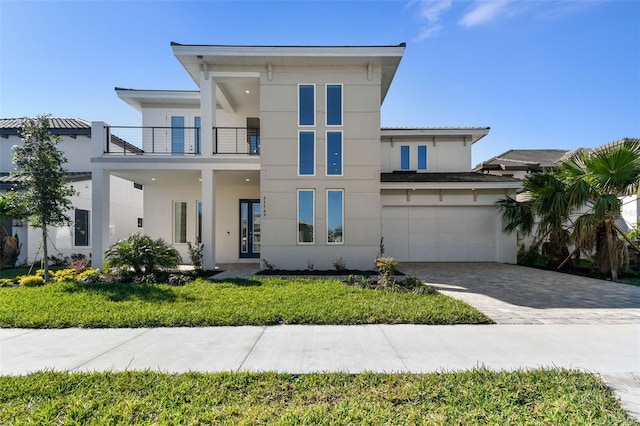 contemporary home featuring a balcony, a front yard, and a garage