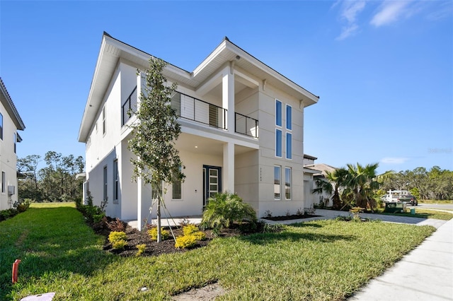 view of front of house with a balcony and a front lawn