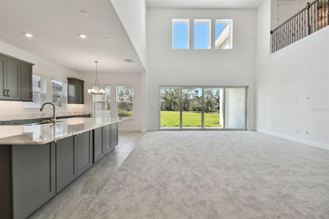 kitchen with a chandelier, a wealth of natural light, light stone counters, and hanging light fixtures