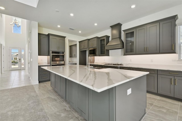 kitchen with a large island with sink, sink, appliances with stainless steel finishes, and custom exhaust hood