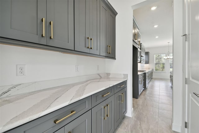 kitchen with light stone countertops, pendant lighting, and gray cabinetry