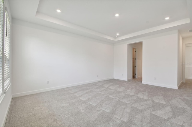 spare room with a tray ceiling and light carpet