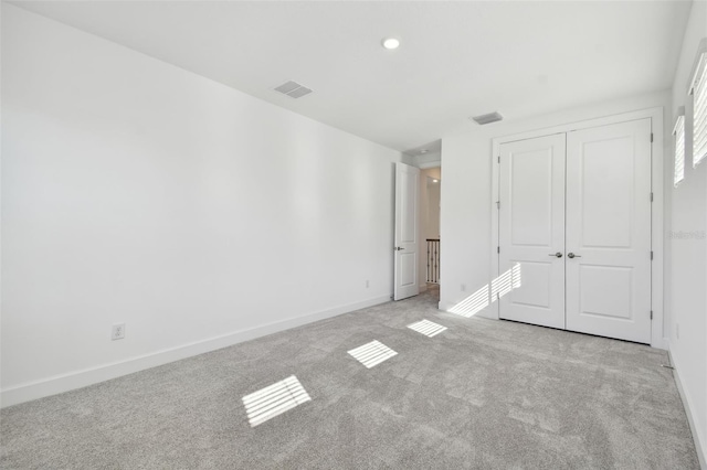 unfurnished bedroom with light carpet and a closet