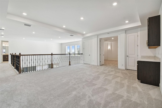 unfurnished living room with a raised ceiling and light carpet