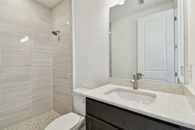 bathroom featuring tiled shower, vanity, and toilet