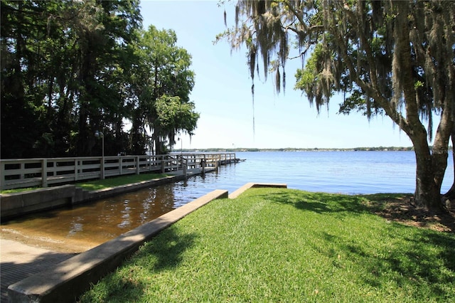 dock area with a water view and a yard