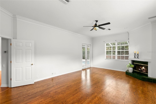 unfurnished living room featuring hardwood / wood-style flooring, ceiling fan, crown molding, and a tiled fireplace