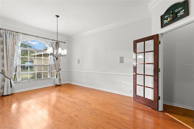 unfurnished dining area with a chandelier, light wood-type flooring, and ornamental molding