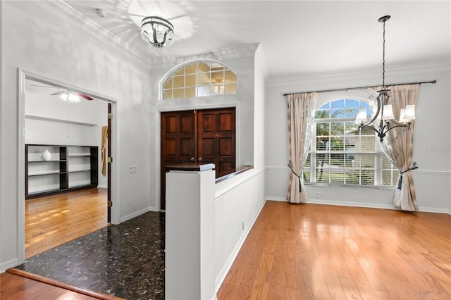 entryway featuring crown molding, light hardwood / wood-style flooring, and ceiling fan with notable chandelier