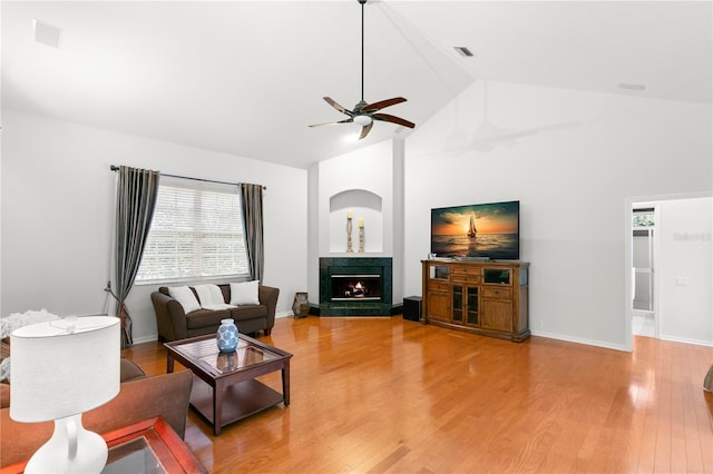 living room with a tile fireplace, ceiling fan, high vaulted ceiling, and hardwood / wood-style flooring