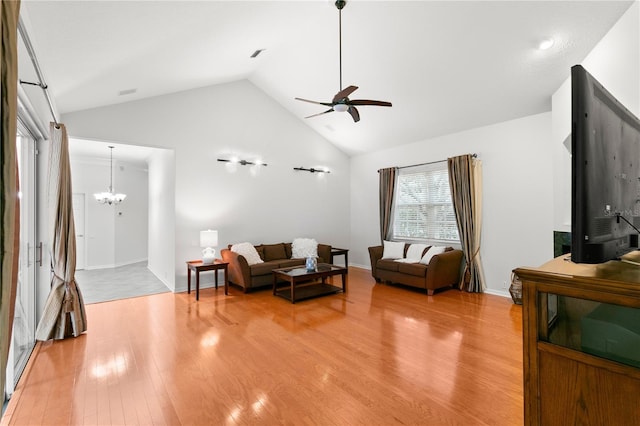 living room featuring hardwood / wood-style flooring, ceiling fan with notable chandelier, and vaulted ceiling