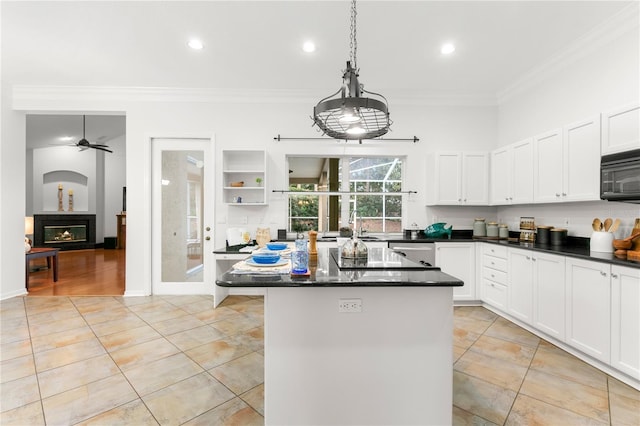 kitchen featuring crown molding, a center island, white cabinets, and decorative light fixtures