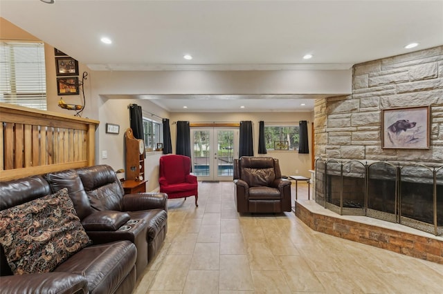 living room featuring french doors, a stone fireplace, and ornamental molding