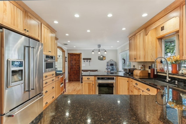 kitchen with kitchen peninsula, appliances with stainless steel finishes, and light brown cabinetry