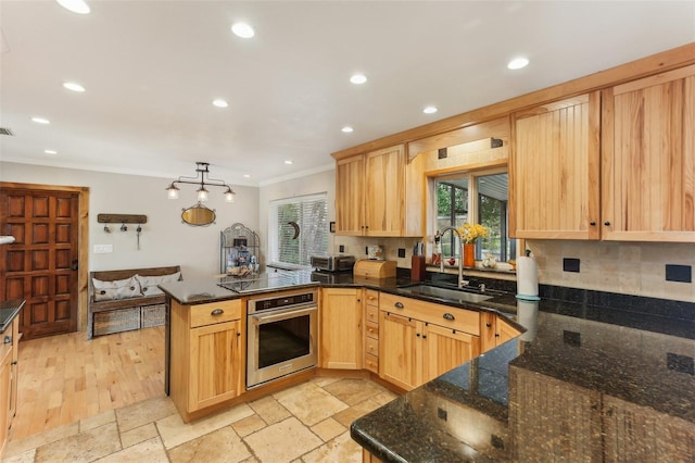 kitchen featuring kitchen peninsula, sink, a healthy amount of sunlight, and stainless steel oven