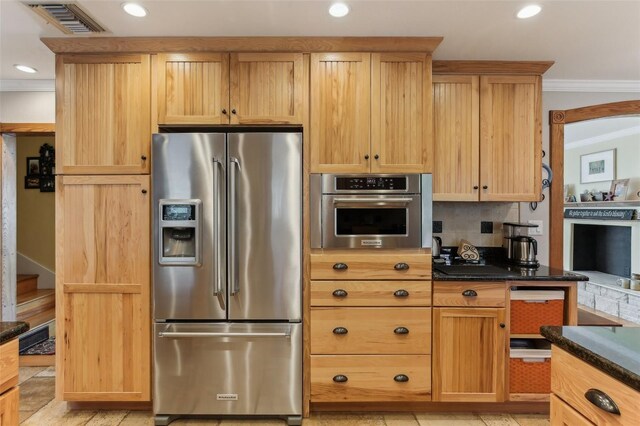 kitchen featuring backsplash, dark stone countertops, crown molding, and appliances with stainless steel finishes