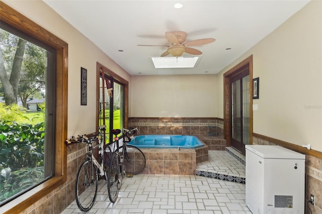 sunroom / solarium featuring a skylight, ceiling fan, and a hot tub