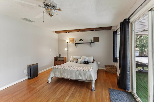 bedroom with hardwood / wood-style floors, a textured ceiling, and ceiling fan