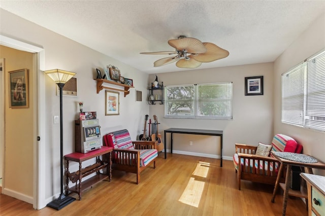 sitting room featuring ceiling fan, light hardwood / wood-style flooring, and a textured ceiling