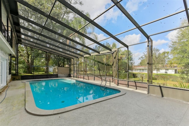 view of swimming pool featuring glass enclosure and a patio