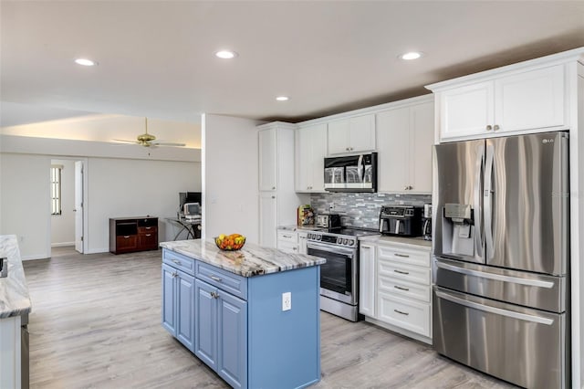 kitchen featuring a kitchen island, light stone countertops, white cabinetry, and stainless steel appliances