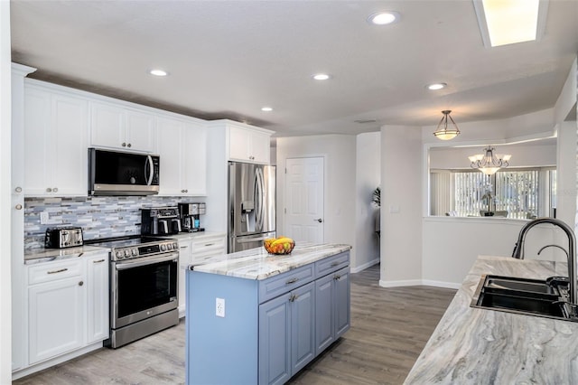 kitchen with a notable chandelier, white cabinetry, sink, and appliances with stainless steel finishes